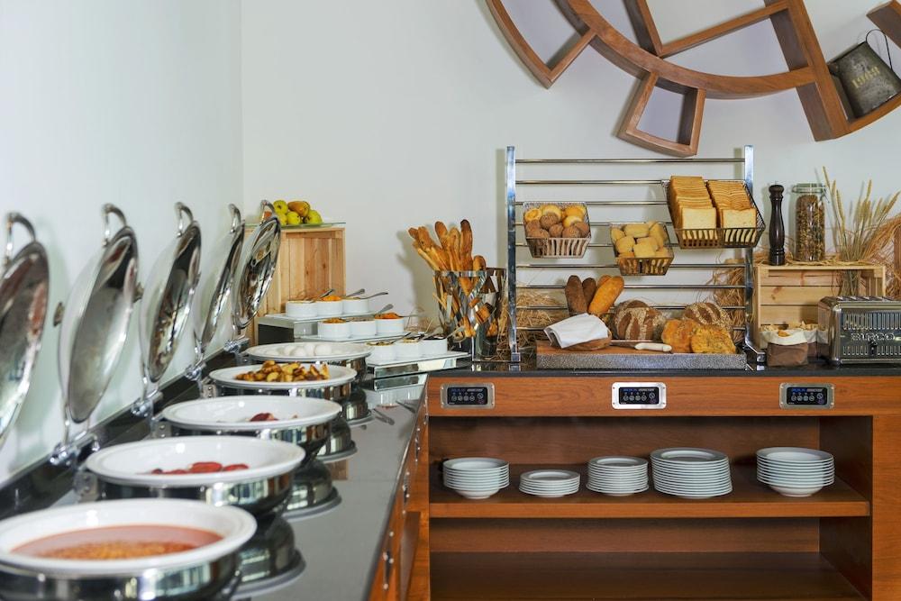 Canal Central Hotel Business Bay Dubaj Zewnętrze zdjęcie The photo shows a dining setup, likely for a breakfast or buffet service. On the left side, there are several silver chafing dishes, which typically contain hot food items. To the right, there are baskets and containers filled with various types of b
