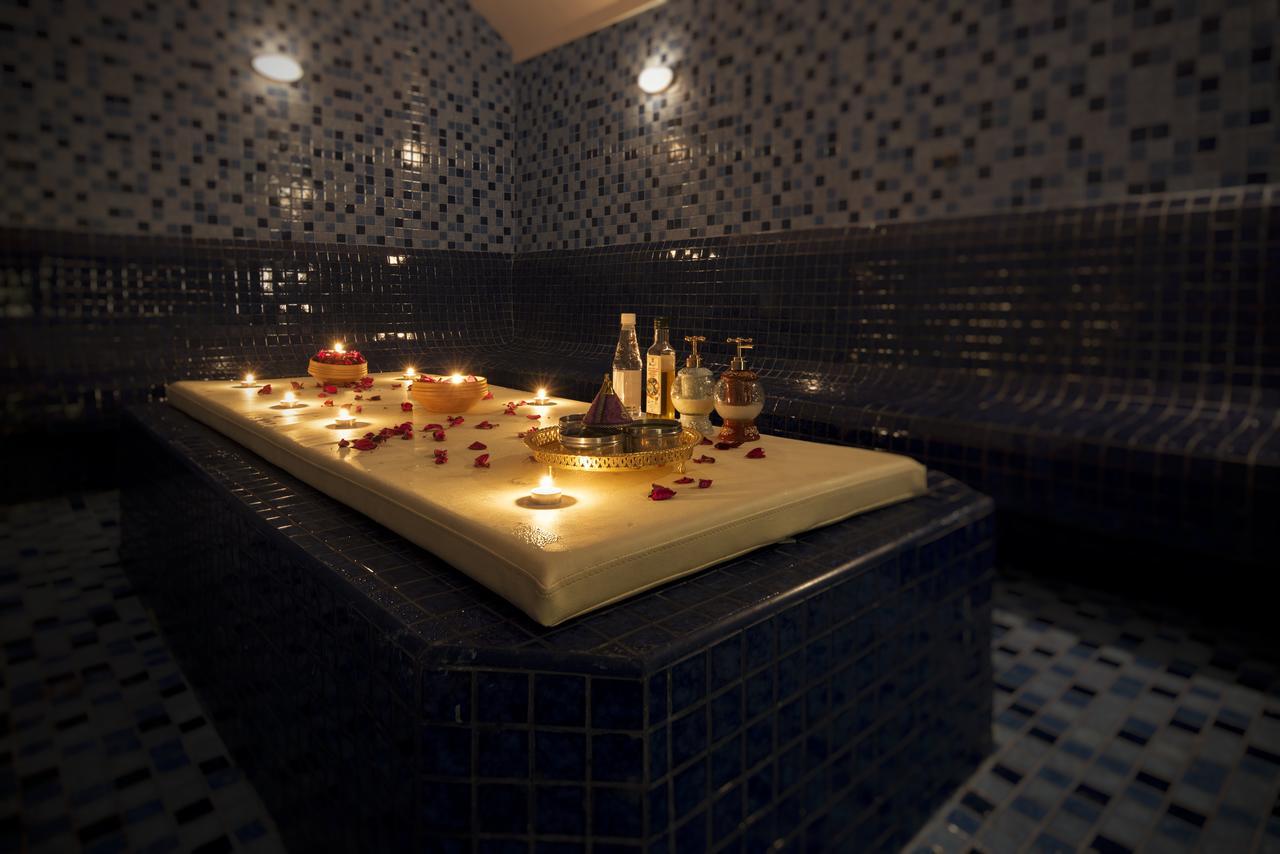 Canal Central Hotel Business Bay Dubaj Zewnętrze zdjęcie The photo features a serene spa setting with a massage table at the center. The table is adorned with candles and decorative elements, such as rose petals, creating a calming atmosphere. Surrounding the table are various bottles, likely containing oi