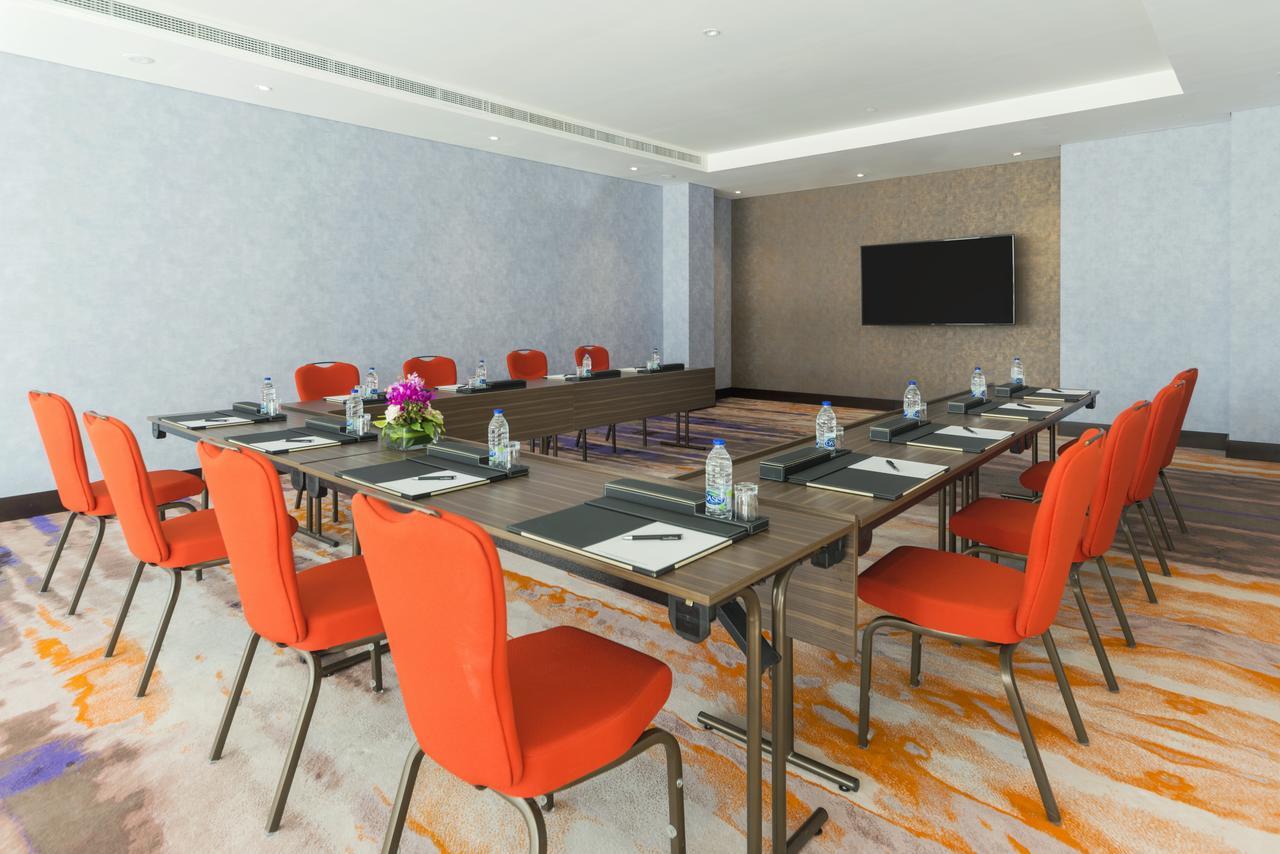 Canal Central Hotel Business Bay Dubaj Zewnętrze zdjęcie The photo shows a conference room designed for meetings or presentations. There is a long rectangular table set up in the center with several chairs around it. The chairs are bright orange, providing a pop of color in the room. On the table, there ar