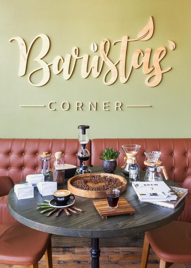 Canal Central Hotel Business Bay Dubaj Zewnętrze zdjęcie The photo depicts a stylish café corner with the words "Brewsty Corner" prominently displayed on a green wall. In front of the wall, there's a brown leather couch and a table that features a variety of coffee-making equipment, including a siphon brew